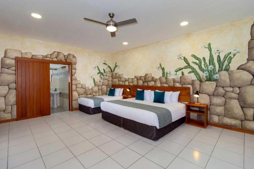 a bedroom with two beds and a stone wall at Plaza Luna Suites in Puerto Ayora