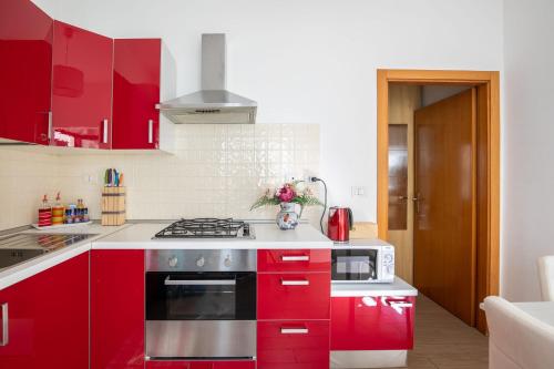 a kitchen with red cabinets and a stove top oven at Bilocale con giardino a 200mt dal mare - HomeUnity in Rimini