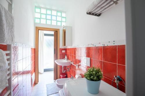 a bathroom with red tiles on the wall and a sink at Bilocale con giardino a 200mt dal mare - HomeUnity in Rimini