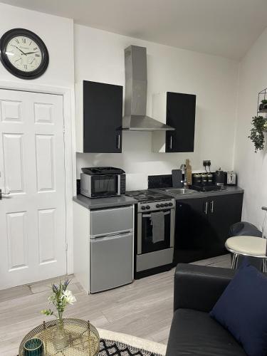 a kitchen with a stove and a clock on the wall at BV Lush Studio At Queensgate Huddersfield Town Centre in Huddersfield