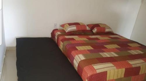 a bed in a room with a red and brown blanket at Village Duplex, Vilas do Atlântico in Lauro de Freitas