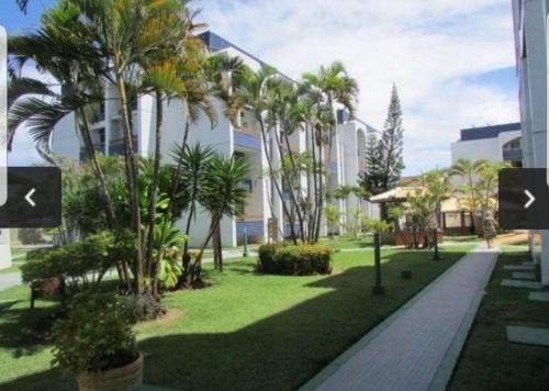 a park with palm trees in front of a building at Village Duplex, Vilas do Atlântico in Lauro de Freitas