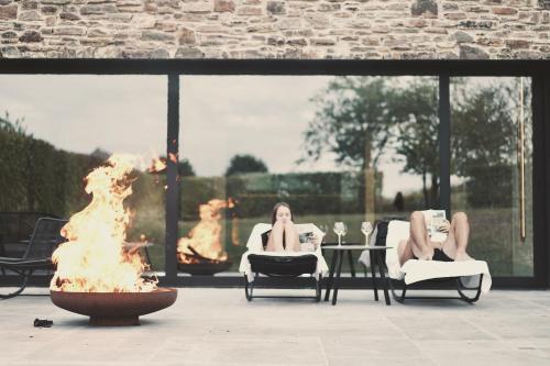 two women sitting in chairs next to a fire pit at Domaine Sur Les Sarts in Ohey