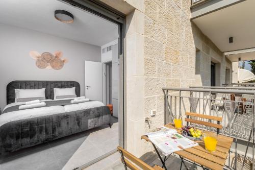 a bedroom with a bed and a balcony with a table at 2BDR W parking shirat haneviim - Mamilla Area sea-u jerusalem in Jerusalem