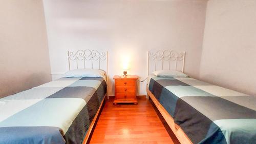 セビリアにあるApartamento Rubens Suite Áticoのベッド2台(ナイトスタンド付)が備わる小さな客室です。