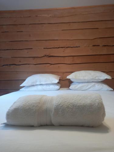 a bed with three pillows and a towel on it at Cabanas Senderos Puyuhuapi in Puerto Puyuhuapi
