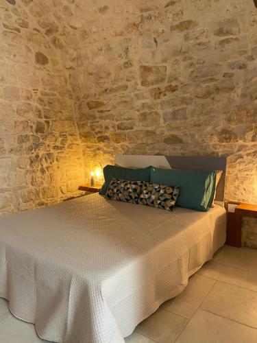 Cama en habitación con pared de piedra en DIMHORA, en Giovinazzo