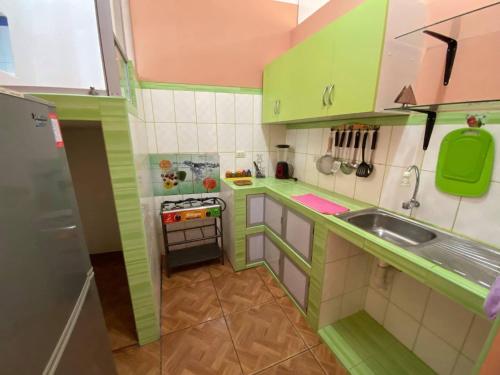 eine kleine Küche mit grünen Schränken und einem Waschbecken in der Unterkunft Departamento amoblado Quillabamba in Quillabamba