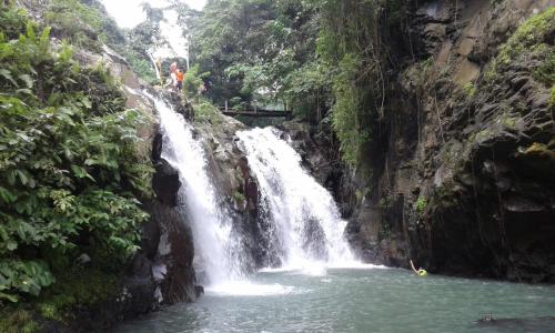 a waterfall with a person standing on top of it at D'kailash Retreat in Singaraja