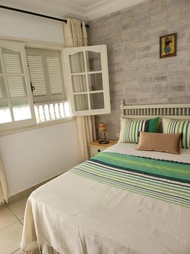 Hotel Dar Al Madina في المهدية: غرفة نوم بسرير ابيض كبير ومخدات مخططة