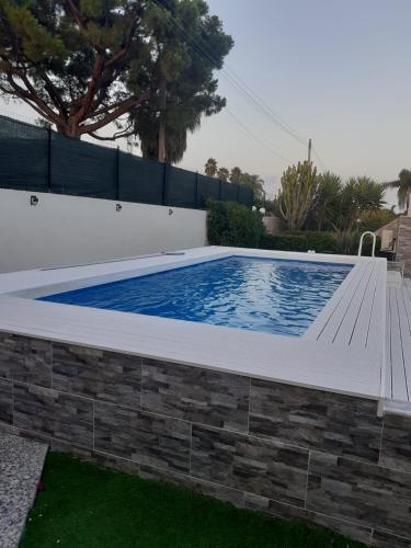 a swimming pool in a backyard with a brick wall at La maison du bonheur in Fontane Bianche