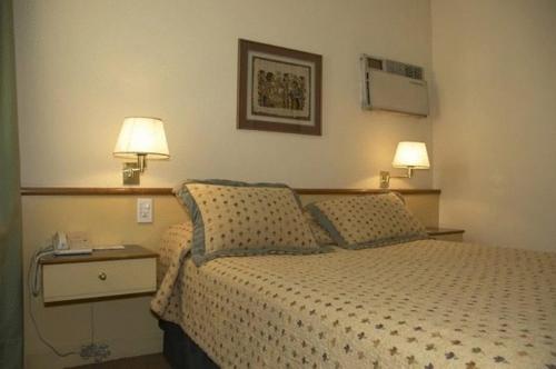 a bedroom with a bed with two lamps on it at Hotel Cervantes in Mendoza