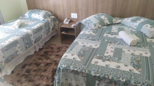 a bedroom with two beds and a table with a night stand at Caçula Palace Hotel in Catalão