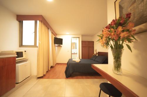 a living room with a couch and a vase of flowers at Apartamentos Galerías in Bogotá