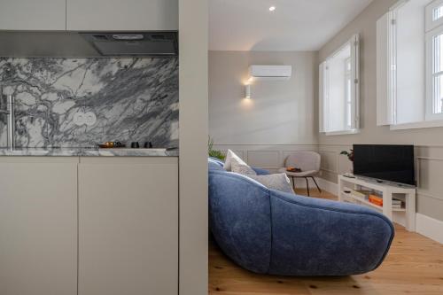 a living room with a blue couch and a tv at As Vizinhas Boutique Apartments in Porto