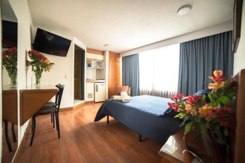 波哥大的住宿－Apartamentos Galerías，酒店客房配有一张床铺、一张桌子和一张书桌。