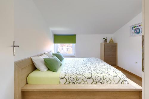 Schlafzimmer mit einem Bett mit grünen und weißen Kissen in der Unterkunft Homestay Pula in Pula