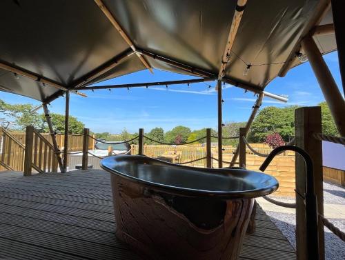 a bath tub sitting on a deck with a canopy at Jungle Book Safari Tent in Tenby