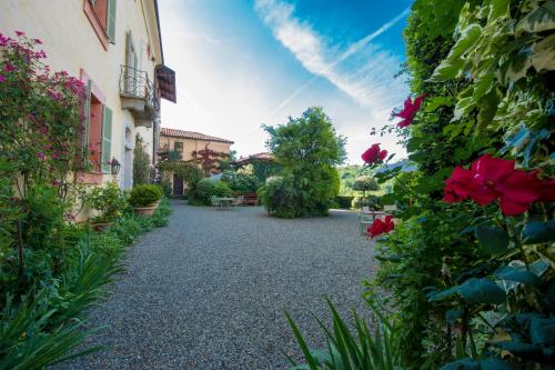 a garden with red flowers and buildings and a pathway at Castello Di Strambinello in Strambinello