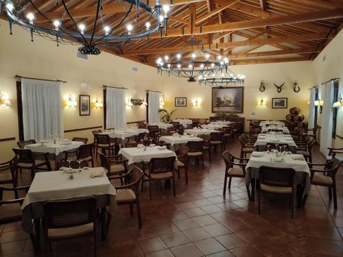 uma sala de jantar com mesas e cadeiras brancas e lustres em Hotel Rural Carlos Astorga em Archidona