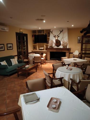 a living room with tables and chairs and a fireplace at Hotel Rural Carlos Astorga in Archidona