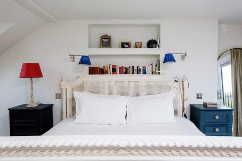 1 dormitorio con cama blanca y almohadas blancas en Veeve - Cyan Gardens en Londres