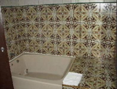 y baño con bañera y pared de azulejos. en Chateau Royale Inn, en Lake Geneva