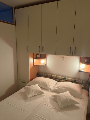 a bed with two white pillows and some cabinets at Apartment Trogir City in Trogir