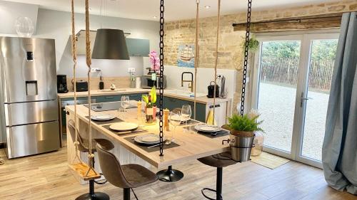 - une cuisine avec une grande table en bois et des chaises dans l'établissement La Grange - Gîte de Prestige La Rochelle, à Saint-Médard-dʼAunis