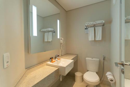 a bathroom with a toilet and a sink and a mirror at Hotel Contemporâneo - Royal Palm Hotels & Resorts in Campinas