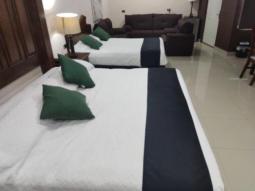 a group of four beds with green pillows in a room at Hotel Posada Santa Fe Sabinas in Sabinas