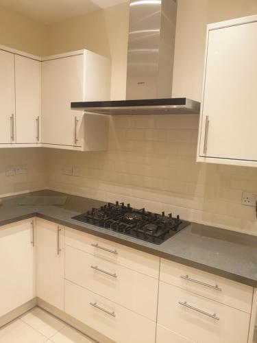 a kitchen with white cabinets and a stove top oven at London Luxury Apartments 5 min walk from Ilford Station, with FREE PARKING & FREE WIFI in Ilford