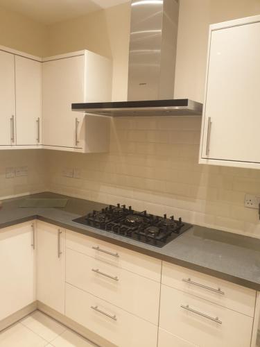 eine Küche mit weißen Schränken und einem Herd mit Backofen in der Unterkunft London Luxury Apartments 5 min walk from Ilford Station, with FREE PARKING & FREE WIFI in Ilford