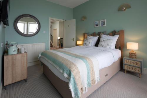 a bedroom with a large bed and a mirror at The Beach Club in Penzance