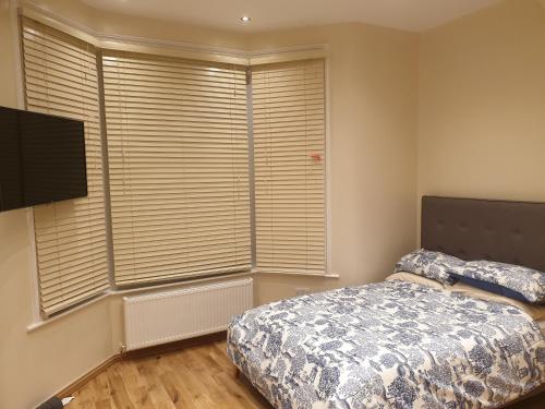 a bedroom with a bed and a large window at London Luxury Apartments 5 min walk from Ilford Station, with FREE PARKING & FREE WIFI in Ilford