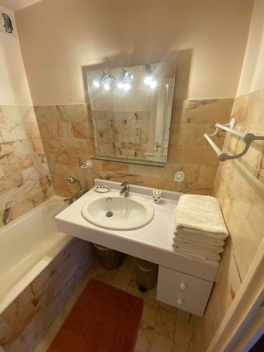 une salle de bain avec un lavabo, un miroir et une baignoire dans l'établissement L'Oustal Coeur de ville, à Le Touquet-Paris-Plage