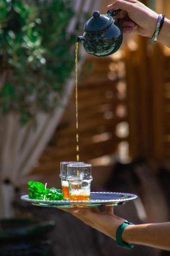 a person holding a glass plate with a drink at Riad Ksar Al Amal & Spa in Marrakech