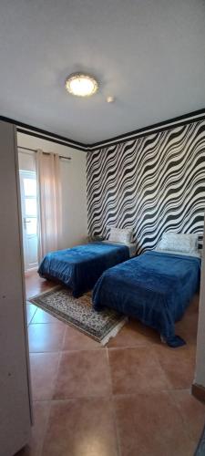 a bedroom with two beds and a striped wall at BananaHouse in Tamri