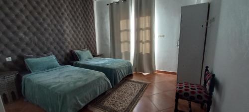 a bedroom with two twin beds and a chair at BananaHouse in Tamri