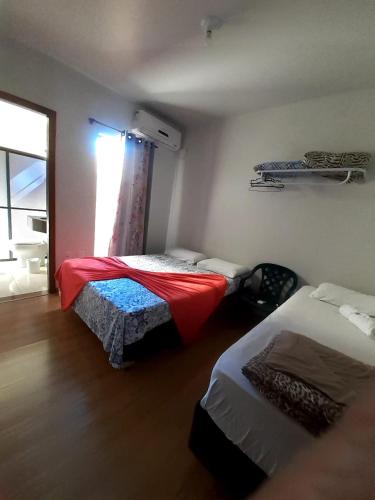 a small room with two beds and a window at D'Casa Hotel e restaurante in Marechal Cândido Rondon