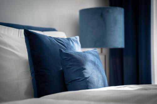 Una cama con almohadas azules y blancas y una lámpara. en Blue Sky Apartment City Center Baden-Baden, en Baden-Baden
