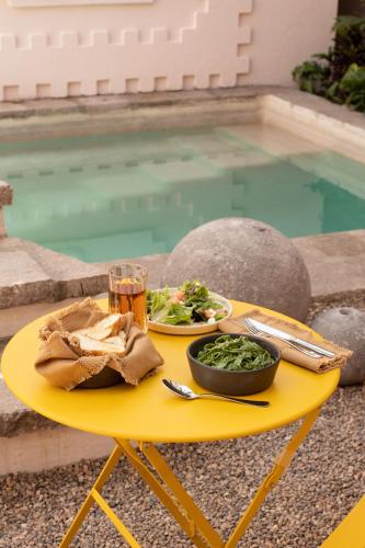 a yellow table with a plate of food and a glass of beer at La Valise San Miguel de Allende, Member of Small Luxury Hotels in San Miguel de Allende
