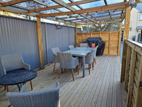 un patio con mesa y sillas en una terraza de madera en THE MEWS Oamaru, en Oamaru