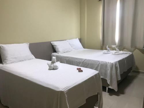 duas camas com lençóis brancos e bichos de peluche em Pousada BarbacoaR na Parnaíba