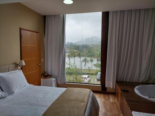 a bedroom with a bed and a sink and a large window at Costa del Mar Hotel Boutique in Miguel Pereira