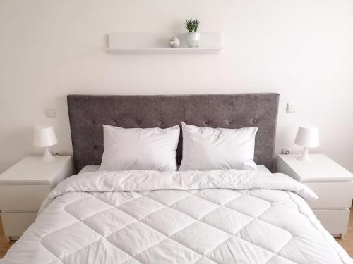 a white bedroom with a large bed with white pillows at Sleep & Rest in Skopje