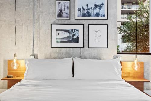 a bedroom with a white bed with pictures on the wall at Pretty Rola 201 Luxury 1B1B w King Bed at Downtown Fort Lauderdale in Fort Lauderdale