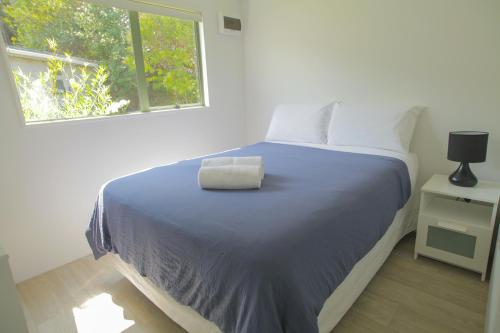 - une chambre avec un lit doté d'une couverture bleue et d'une fenêtre dans l'établissement Oamaru Bay Tourist Park, à Coromandel