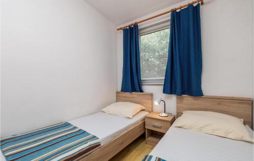 two beds in a bedroom with blue curtains and a window at 2 Bedroom Awesome Apartment In Mandre in Mandre