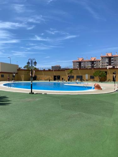 a large swimming pool with a green floor and a building at APARTAMENTO EN LOS CRISTIANOS - FREE WIFI in Los Cristianos